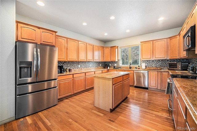 1155 S Balsam St, Lakewood, CO 80232 - kitchen with appliances with stainless steel finishes, a center island, recessed lighting, light wood-type flooring, and tasteful backsplash