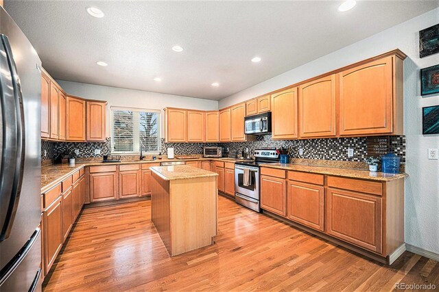 1155 S Balsam St, Lakewood, CO 80232 - kitchen with light wood-style floors, a center island, stainless steel appliances, recessed lighting, and tasteful backsplash