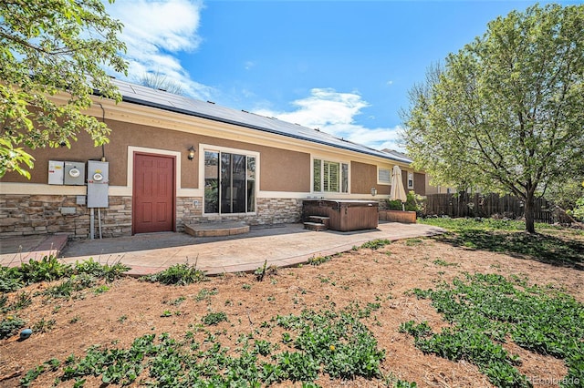 1155 S Balsam St, Lakewood, CO 80232 - rear view of house with a hot tub, stone siding, stucco siding, roof mounted solar panels, and a patio