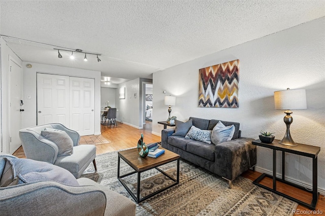 3047 W 47th Ave Unit 112, Denver, CO 80211 - living room featuring wood finished floors, a textured ceiling, baseboards, and track lighting