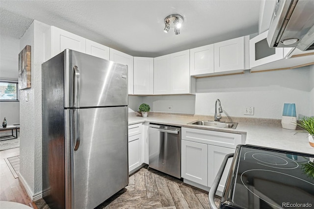 3047 W 47th Ave Unit 112, Denver, CO 80211 - kitchen featuring stainless steel appliances, a sink, light countertops, white cabinets, and a textured ceiling