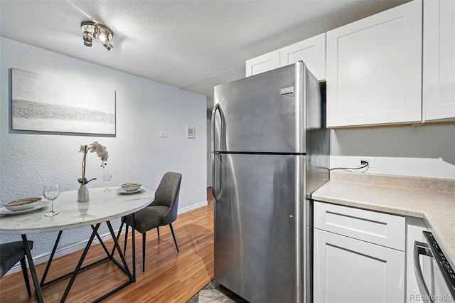 3047 W 47th Ave Unit 112, Denver, CO 80211 - kitchen featuring freestanding refrigerator, a textured wall, white cabinetry, a textured ceiling, and light countertops