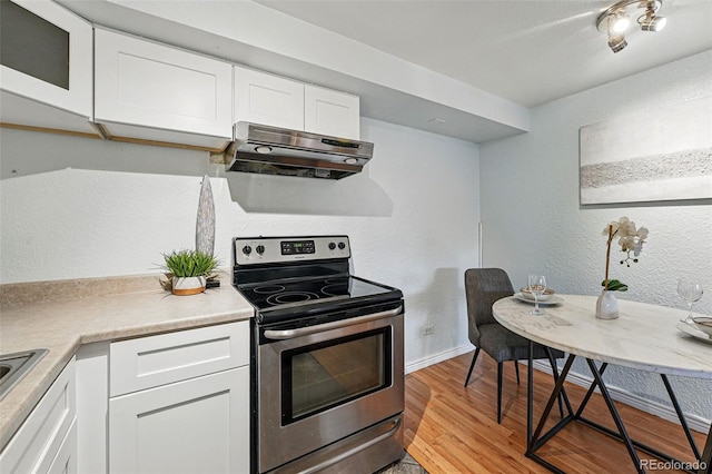 3047 W 47th Ave Unit 112, Denver, CO 80211 - kitchen with stainless steel electric range, under cabinet range hood, white cabinets, light wood finished floors, and light countertops