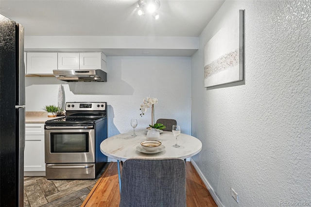 3047 W 47th Ave Unit 112, Denver, CO 80211 - kitchen with stainless steel range with electric stovetop, under cabinet range hood, white cabinetry, a textured wall, and light countertops