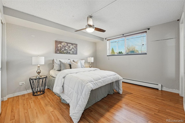 3047 W 47th Ave Unit 112, Denver, CO 80211 - bedroom with baseboard heating, light wood-type flooring, baseboards, a textured ceiling, and ceiling fan