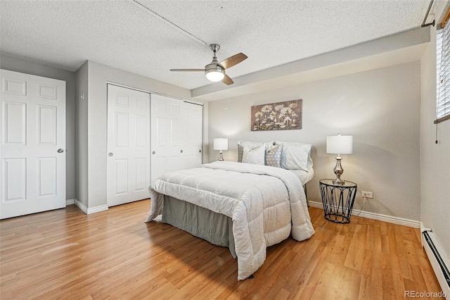 3047 W 47th Ave Unit 112, Denver, CO 80211 - bedroom with a baseboard radiator, baseboards, light wood-type flooring, a closet, and a textured ceiling