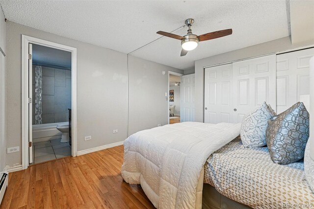 3047 W 47th Ave Unit 112, Denver, CO 80211 - bedroom with wood finished floors, a baseboard heating unit, baseboards, a textured ceiling, and ensuite bath