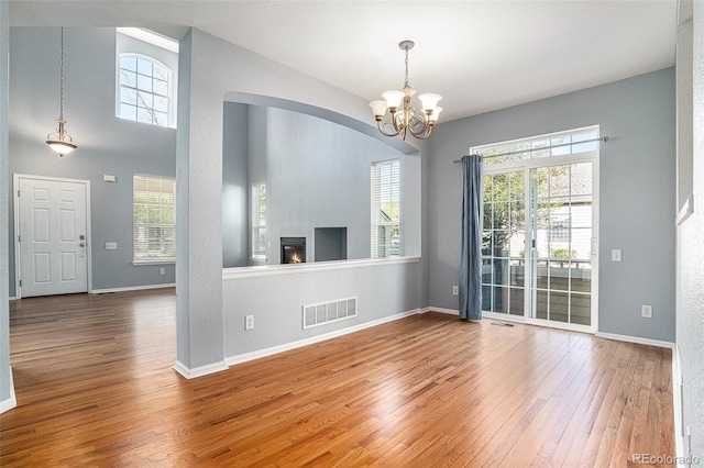 unfurnished living room with hardwood / wood-style flooring, healthy amount of natural light, and a chandelier
