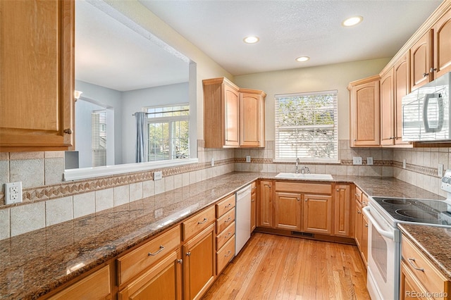 kitchen featuring white appliances, a sink, recessed lighting, plenty of natural light, and light wood-style floors