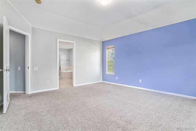 unfurnished bedroom with carpet flooring, baseboards, and ensuite bath