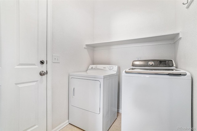 laundry area with washing machine and clothes dryer and baseboards