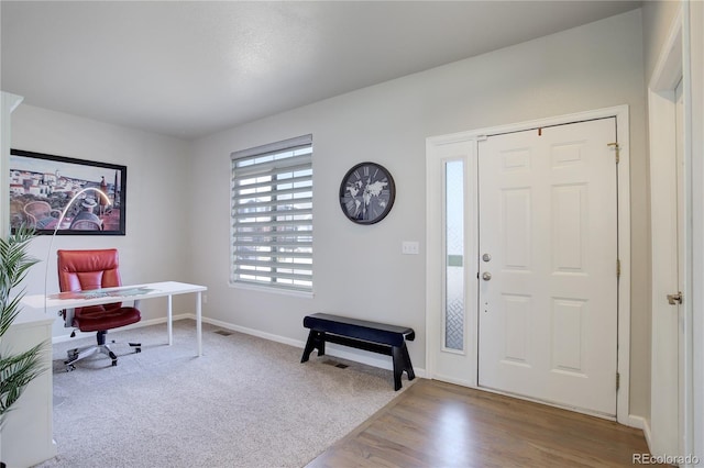 carpeted entryway featuring wood finished floors and baseboards