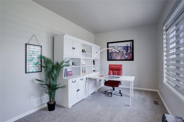 office space with baseboards, visible vents, and light carpet