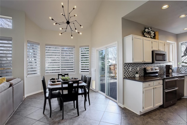 kitchen featuring backsplash, dark countertops, white cabinetry, appliances with stainless steel finishes, and an inviting chandelier