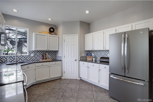 kitchen with white cabinetry, freestanding refrigerator, and a sink