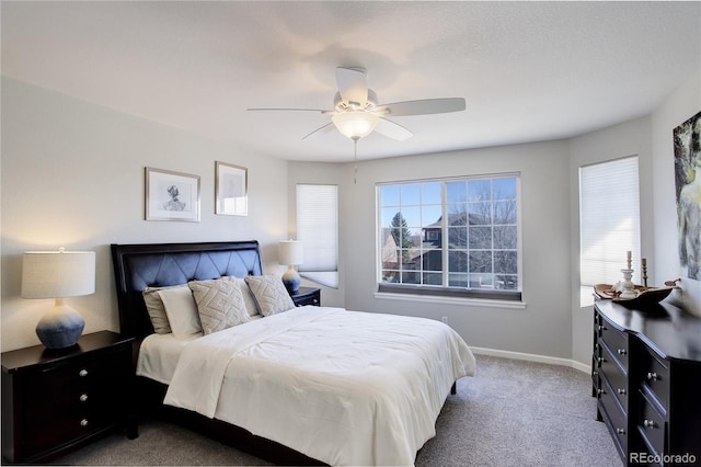 bedroom featuring baseboards, multiple windows, light colored carpet, and ceiling fan