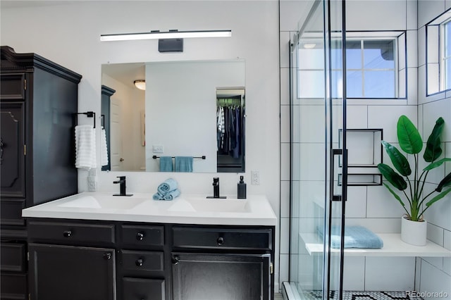 bathroom featuring double vanity, a stall shower, and a sink