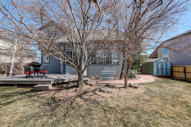 back of property featuring fence, a shed, an outdoor structure, a deck, and a lawn