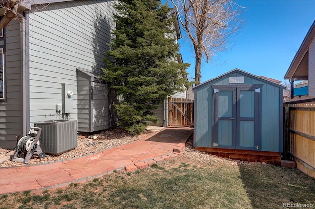 view of yard with fence, central air condition unit, an outbuilding, a storage unit, and a gate