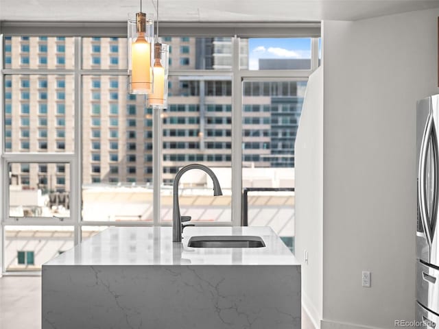 kitchen with a sink, freestanding refrigerator, and pendant lighting