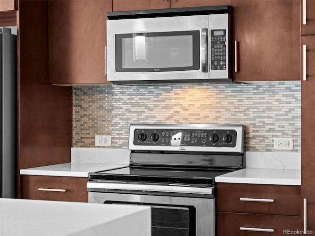 kitchen featuring dark brown cabinets, modern cabinets, light countertops, tasteful backsplash, and stainless steel appliances