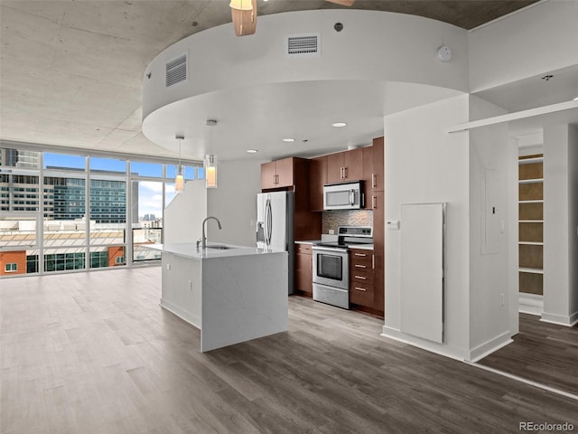 kitchen with a sink, appliances with stainless steel finishes, wood finished floors, and visible vents