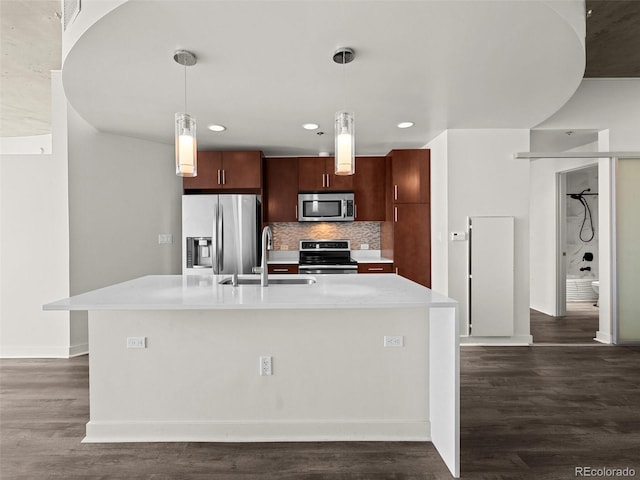 kitchen with light countertops, appliances with stainless steel finishes, a sink, and dark wood finished floors