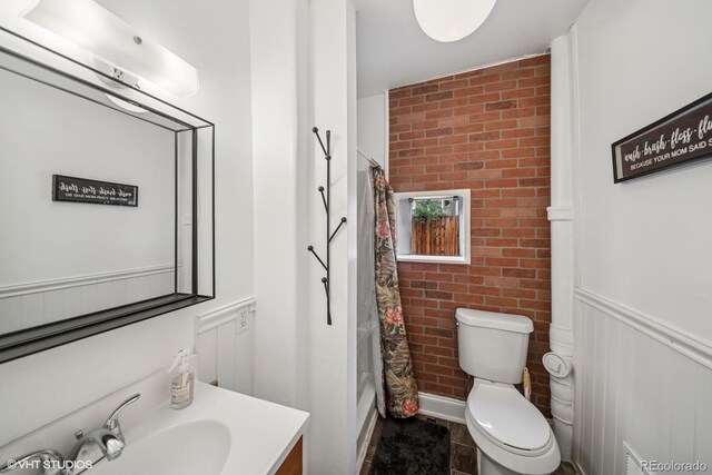113 S 4th Ave, Brighton, CO 80601 - bathroom with vanity, toilet, brick wall, and shower / tub combo