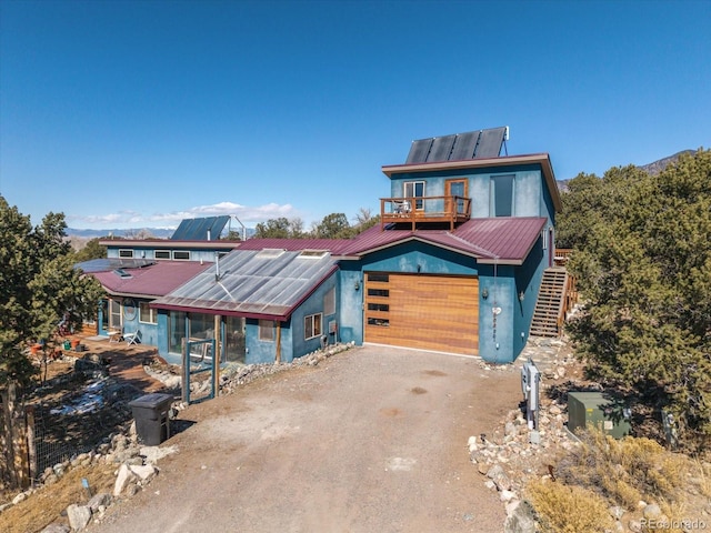 view of front of property featuring metal roof, a garage, and dirt driveway