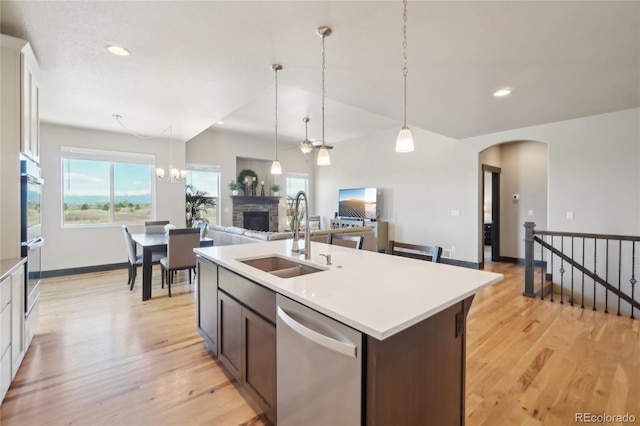 kitchen featuring a fireplace, plenty of natural light, a sink, light wood-style flooring, and appliances with stainless steel finishes