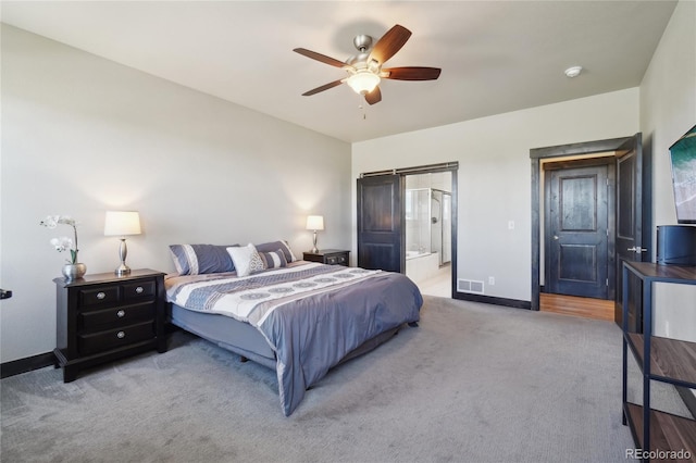 carpeted bedroom with ceiling fan, baseboards, visible vents, and ensuite bathroom