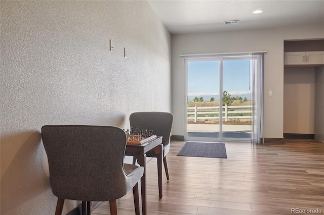 dining room featuring baseboards, a textured wall, wood finished floors, and visible vents
