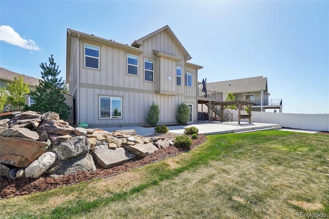 back of property with board and batten siding, a deck, stairway, fence, and a patio