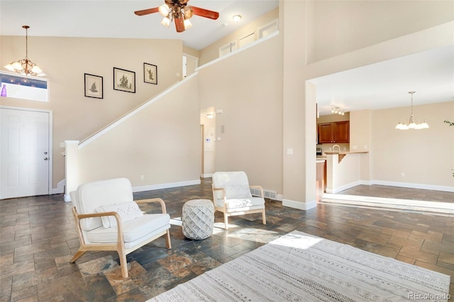 living area with ceiling fan with notable chandelier and high vaulted ceiling