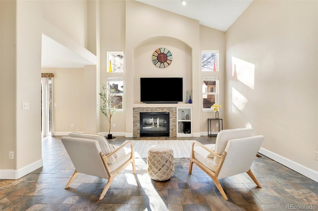 living room with a stone fireplace and high vaulted ceiling