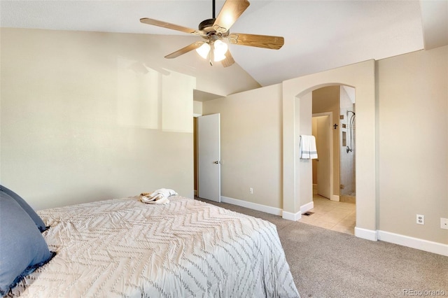 carpeted bedroom with ceiling fan, vaulted ceiling, and ensuite bath