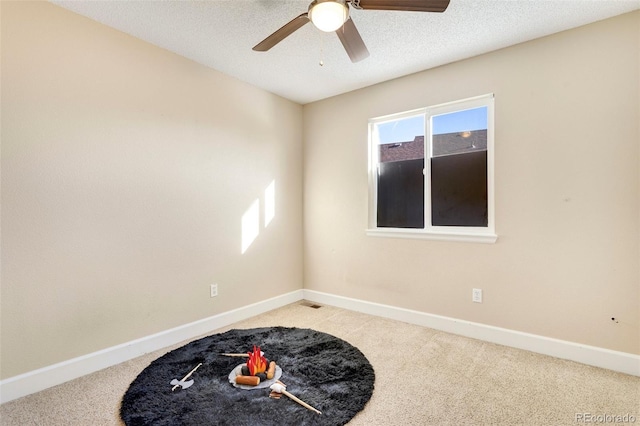 carpeted empty room with ceiling fan and a textured ceiling