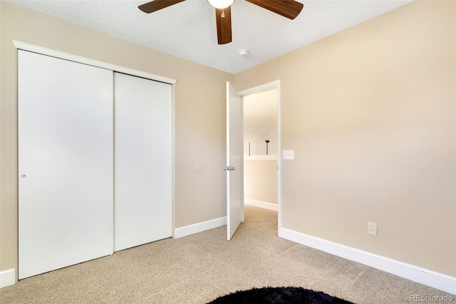 unfurnished bedroom with ceiling fan, carpet floors, a textured ceiling, and a closet