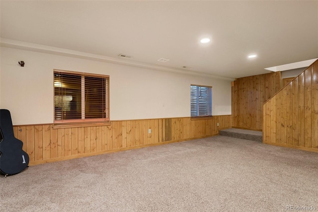 spare room featuring carpet flooring and wooden walls