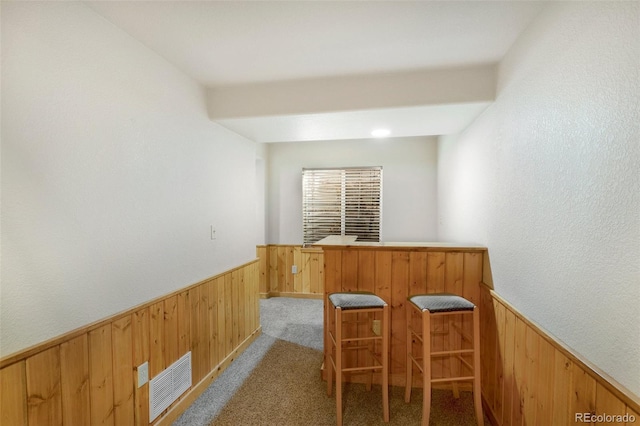 bar featuring light carpet and wooden walls