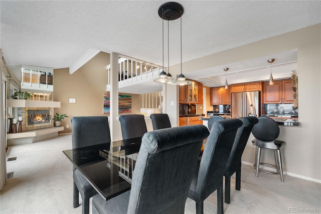 7160 W Stetson Pl Unit 27, Littleton, CO 80123 - dining area with light carpet, a glass covered fireplace, a textured ceiling, and baseboards