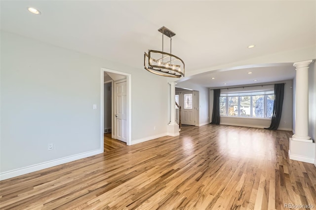 unfurnished living room featuring an inviting chandelier and light hardwood / wood-style floors