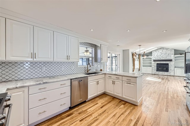 kitchen with sink, white cabinets, stainless steel appliances, and a fireplace