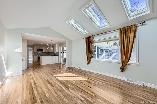 unfurnished living room featuring light wood-type flooring, an inviting chandelier, and lofted ceiling with skylight