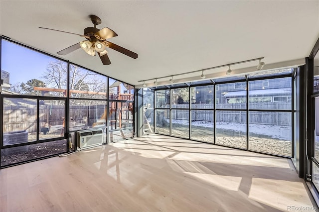 unfurnished sunroom with ceiling fan, cooling unit, a wealth of natural light, and rail lighting