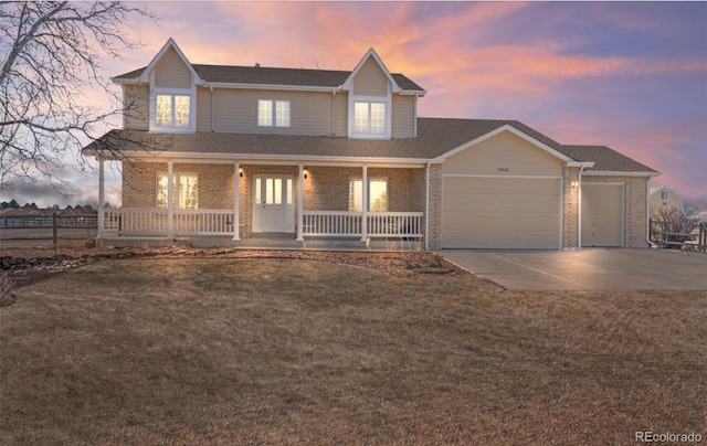 view of front of property with a porch, concrete driveway, a lawn, and a garage