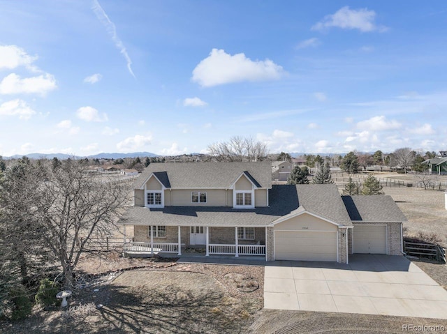 traditional home featuring a mountain view, a garage, covered porch, brick siding, and driveway