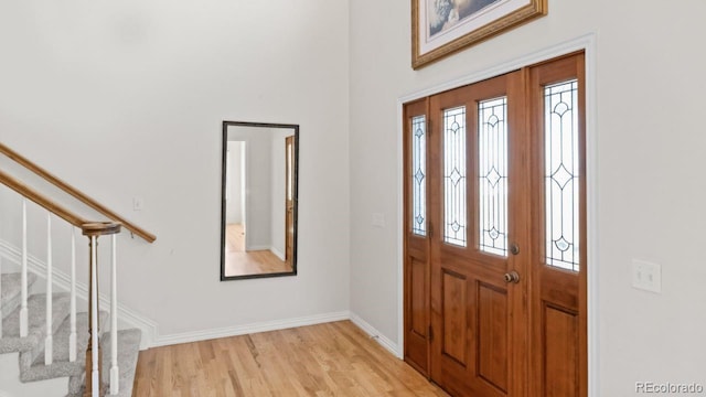 entrance foyer with stairs, baseboards, and light wood-style floors