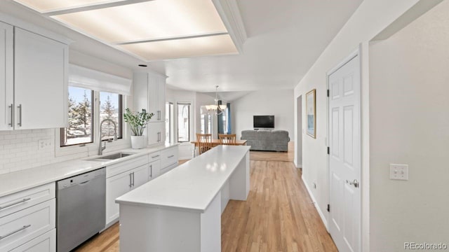 kitchen featuring backsplash, a center island, light countertops, stainless steel dishwasher, and a sink