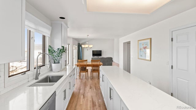 kitchen featuring a chandelier, light countertops, a sink, and white cabinets